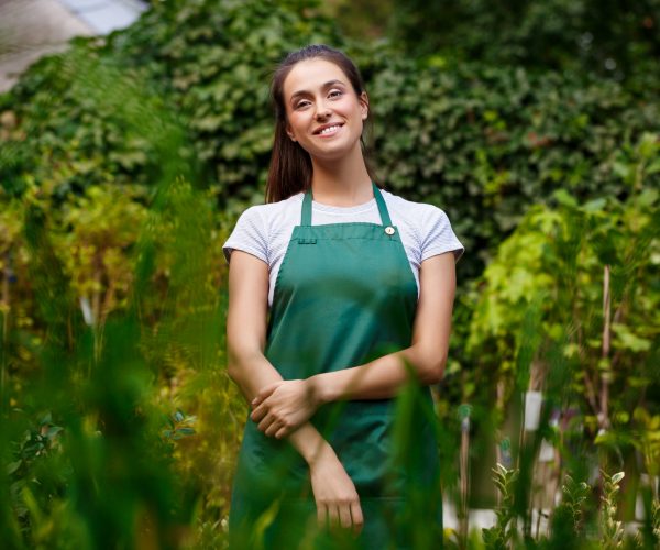 Young beautiful florist posing, smiling among flowers. Young beautiful female florist posing, smiling among flowers.